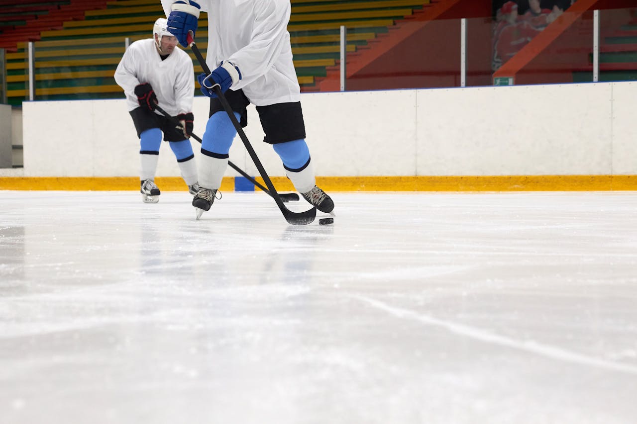 Players actively competing in an ice hockey game inside a rink with visible audience.