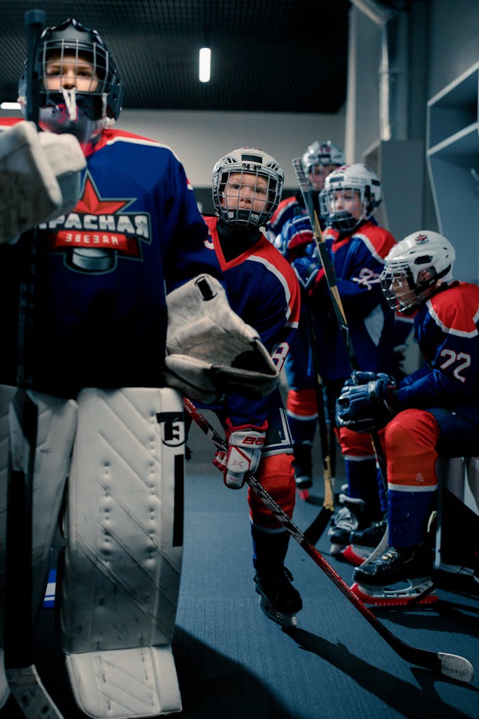 Youth hockey team getting ready with safety gear in the locker room.