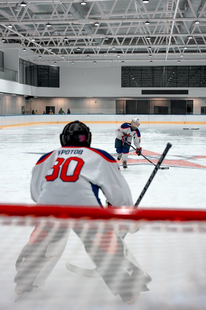 Dynamic ice hockey game indoors with a focus on the goalie and player interaction.